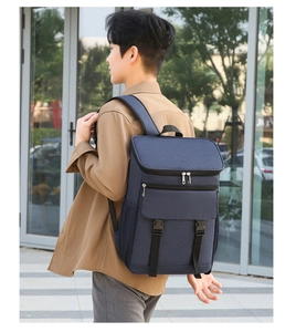 Outdoor view of a navy blue insulated thermal backpack with buckle straps and mesh side pockets