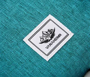 Detail von blauem Textilgewebe mit quadratischem Vanaheimr-Berglosgo auf dem Rucksack