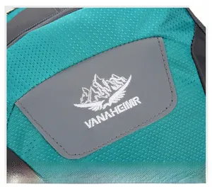 Detail of embroidered mountain logo and VANAHEIMR brand name on blue nylon hiking backpack