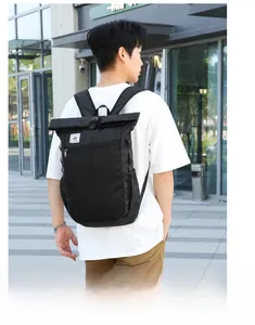 Detail view of a black roll-top outdoor backpack showing durable fabric and functional pockets