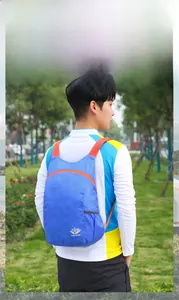 Blauer leichter faltbarer Reise-Rucksack mit orangefarbenen Details im Park fotografiert