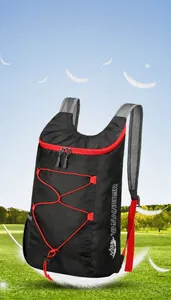 Lightweight foldable travel backpack with red bungee cords floating over green grass