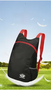 Leichter faltbarer Rucksack in Schwarz und Rot über einer malerischen grünen Wiese