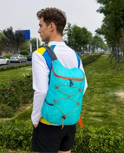 Outdoor foldable backpack in bright cyan nylon with orange elastic cords and mesh straps