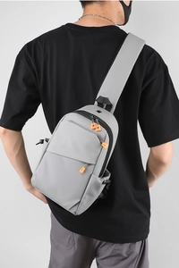 Détail du sac bandoulière gris avec zips orange vif et bandoulière large respirante