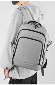 Close-up of minimalist light gray backpack with multi-compartment design and water-resistant fabric