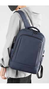 Close-up of water-resistant navy blue business backpack worn by model on grey background