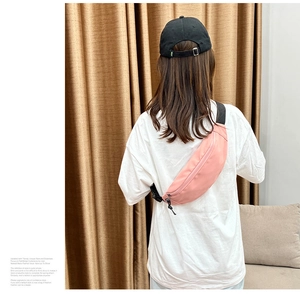 Vue détaillée du sac bandoulière en nylon rose clair avec bandoulière noire sur un modèle