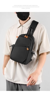 Détail d'un sac de poitrine noir minimaliste avec fermetures éclair orange et sangle réglable