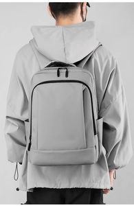 Minimalist grey water-resistant commuter backpack shown on model for ergonomic fit