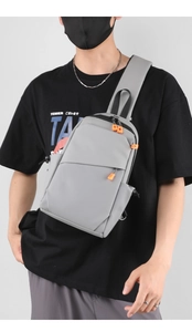 Gros plan détaillé du sac bandoulière gris au design minimaliste avec fermetures orange