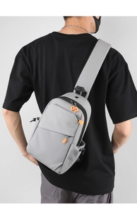 Détail du sac à bandoulière en nylon gris avec zips orange et texture imperméable