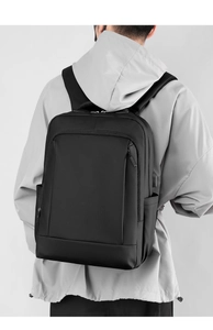 Detail view of water-resistant black business backpack worn by person for daily commute
