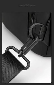 Détail du crochet en métal noir mat et de la bandoulière en nylon sur le sac de poitrine