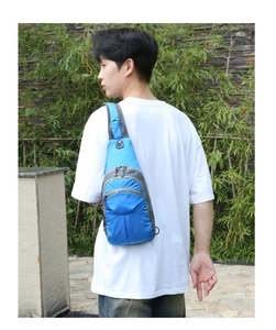 Blue hiking chest bag with multiple zipper compartments and headphone port on male model