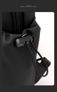 Détail du sac de poitrine en nylon noir montrant le cordon de serrage et le zip métal