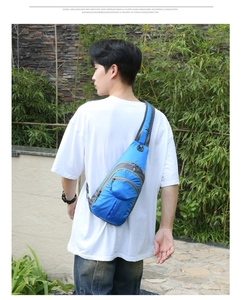 Blue and grey hiking chest pack worn by male model on a white shirt in outdoor setting