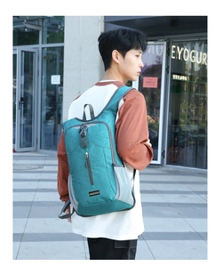 Side view of a blue lightweight foldable hiking backpack worn by a model in city setting