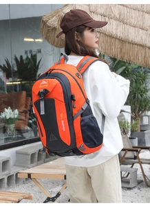 Side view of a 40L orange and black hiking backpack on model in outdoor scene