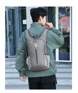 Outdoor shot of a lightweight grey foldable backpack worn by a model for hiking and camping