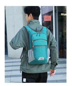 Outdoor foldable teal hiking backpack shown on model with focus on the side storage pockets