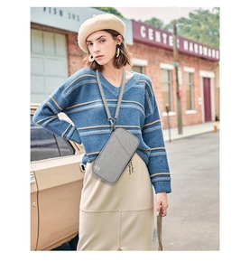 Grey travel neck pouch with adjustable strap shown in a stylish outdoor street setting