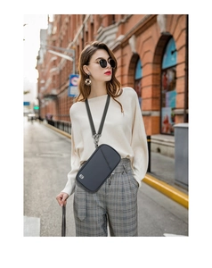 Lifestyle shot of a grey RFID crossbody passport bag with adjustable strap for travel