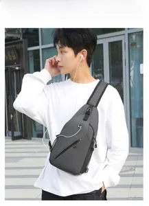 Detail of grey sling bag featuring headphone port and multiple zipper compartments