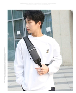 Detail view of dark grey crossbody bag with reflective safety strip on a male model