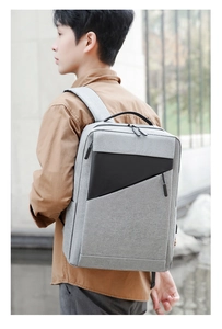 Young man wearing grey business laptop backpack with black geometric pocket in city