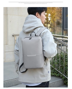 Zaino grigio chiaro minimalista in tessuto impermeabile indossato dal modello