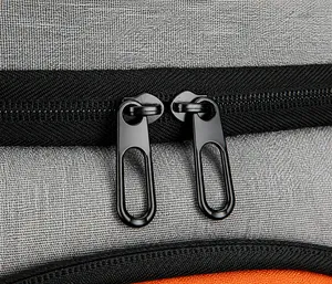 Détail des fermetures éclair métalliques bidirectionnelles sur le sac à dos gris