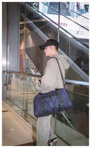 Detalle del bolso de viaje azul grande con cordones elásticos y correas de nailon negro