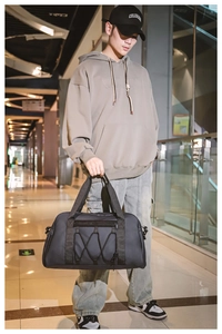 Bolsa de viaje negra de gran capacidad para deporte mostrada por un modelo en la terminal