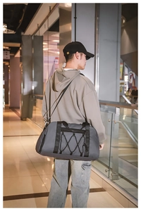 Bolso de viaje gris de gran capacidad con correas elásticas mostrado por modelo en centro