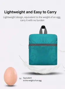 Macro shot of ultra-lightweight foldable teal backpack with feather and egg for weight contrast