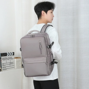 Sac à dos voyage gris en nylon étanche avec boucles latérales porté par un homme