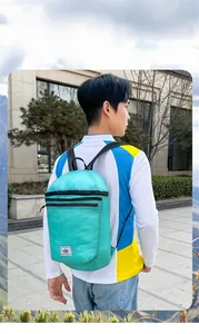 Foldable mint green lightweight travel backpack worn by male model in outdoor scenic view
