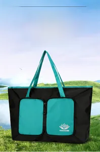 Détail d'un sac de voyage pliable noir et vert avec logo de marque en plein air
