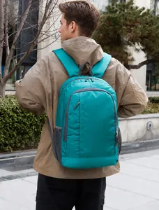 Detail view of a bright cyan lightweight outdoor backpack with side mesh pockets on a model