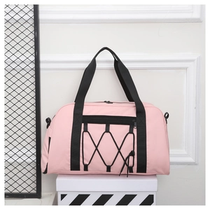 Detalle de bolsa de viaje rosa con correas negras y tela de nailon resistente para deportes