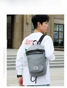 Detail of grey lightweight waterproof folding backpack shown on model for outdoor travel