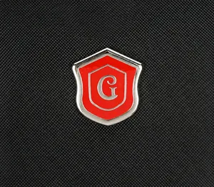 Detailed macro view of the red shield metal logo on black oxford fabric backpack