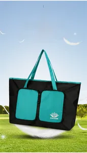 Sac de voyage pliable léger noir et cyan flottant sur l'herbe montrant sa légèreté