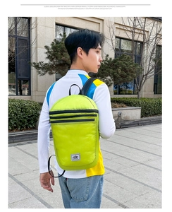 Detail view of a neon yellow folding backpack on male model for outdoor sports and travel