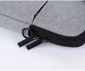 Detail of grey fabric laptop bag featuring durable dual metal zippers and smooth texture