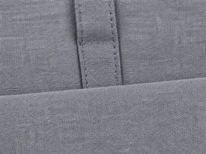 Primer plano de costuras dobles reforzadas en la tela gris de un maletín para PC