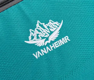 Detailopname van het berglogo op de groenblauwe ripstop stof van de wandelrugzak