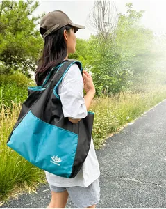 Detail of a lightweight foldable black and teal crossbody travel bag used outdoors