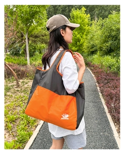 Outdoor shot showing details of the large capacity folding tote bag with orange accents